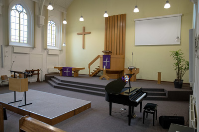 De kerkzaal voorin met podium en piano